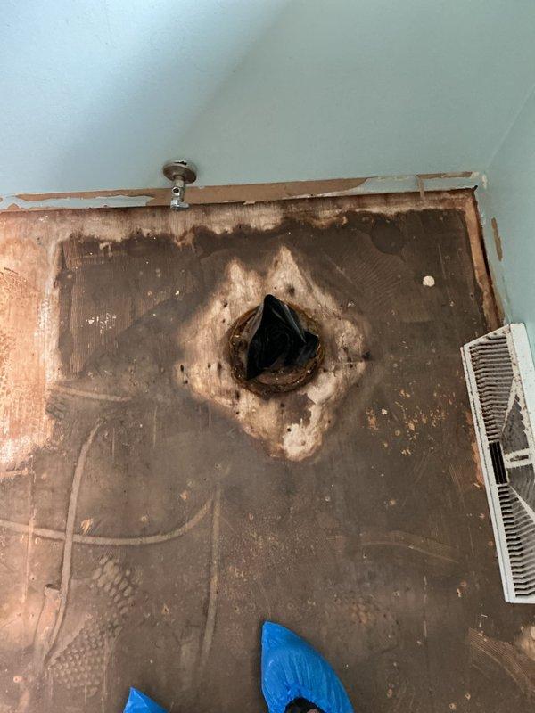 Responded to water leak investigation with ceiling access already opened from previous visit. Documented extensive water damage to subfloor and surrounding areas, including significant staining and deterioration around central penetration point. Inspected attic space and HVAC ductwork above affected area, noting moisture staining on plywood sheathing and aged ductwork components with visible wear. Photographed damaged areas showing concentrated water intrusion pattern on exposed subflooring and compromised building materials. Area requires full damage assessment to determine extent of repairs needed for affected flooring, subfloor, and potential structural components before remediation can proceed.