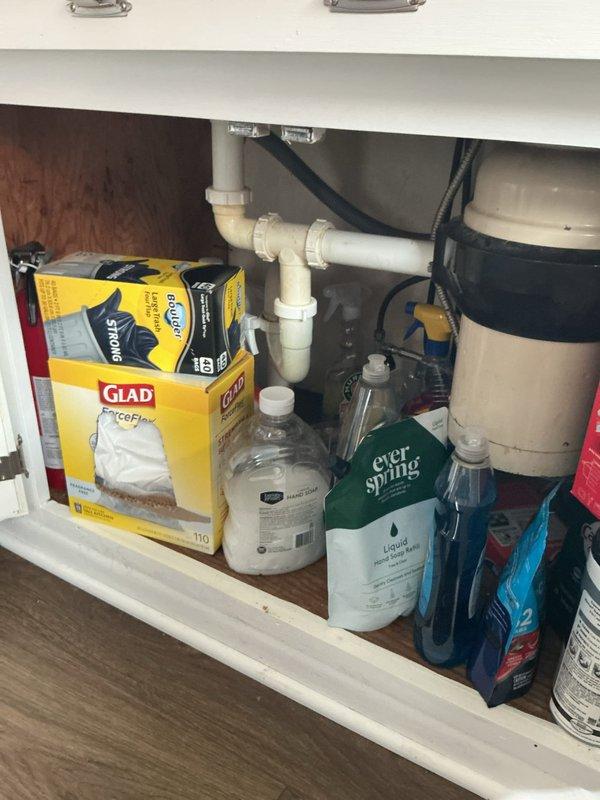 Responded to complaint of sewage odor in residence with no identifiable source. Conducted thorough inspection of kitchen sink plumbing system, including P-trap assembly, drain lines, and garbage disposal connections beneath double-basin sink. Verified proper trap configuration and checked for dry traps, leaking seals, and venting issues that could allow sewer gases to enter living space. Documented existing plumbing conditions with photographic evidence showing standard PVC drain assembly and under-sink storage area.