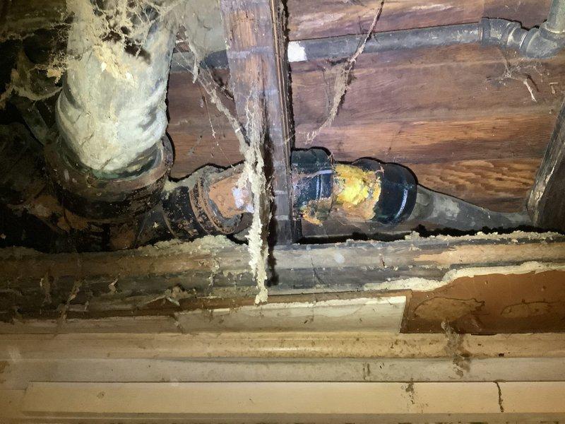 Responded to bathtub drainage concern in century-old residence where customer reported possible blockage and visible hole in drain line beneath tub. Accessed crawl space beneath bathroom fixture to inspect drain assembly and trap configuration. Upon inspection, identified compromised drain piping with deterioration evident in the drainage system, along with aged plumbing components consistent with the structure's age. Documented existing conditions through photography showing exposed drain lines, trap assembly, and surrounding structural elements in the under-floor cavity. Assessed entire visible drain line run for additional damage, corrosion, or integrity issues that could contribute to drainage problems or future failures. Provided customer with findings regarding the damaged drain line section and recommendations for necessary trap replacement and drain line repairs to restore proper function and prevent water damage to floor structure and surrounding areas.