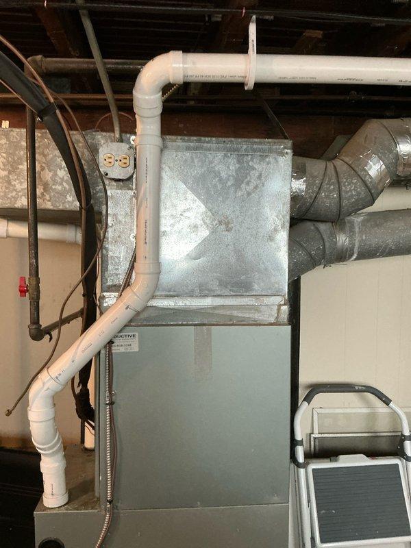 Conducted on-site evaluation for replacement estimate of residential split HVAC system, including both furnace and air conditioning unit, both approximately 10 years old. Assessed existing equipment configuration consisting of basement-installed forced air furnace with plenum assembly and exterior-mounted AC condenser unit positioned beneath wooden deck structure. Documented current system specifications, installation conditions, and equipment placement for comprehensive replacement proposal development.