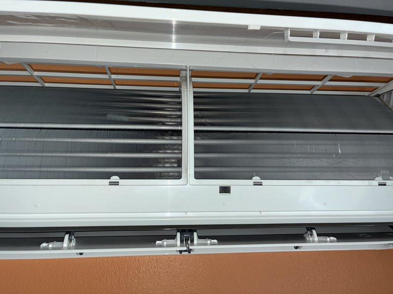 Performed scheduled maintenance on 1.5-year-old mini split heat pump system. Removed indoor unit cover to access evaporator coil and internal components, inspected heat exchanger fins for cleanliness and damage, verified proper airflow and filter condition. Inspected refrigerant lines and mounting brackets, confirmed secure installation and proper insulation of copper line set. All components found in good operating condition with no issues identified.