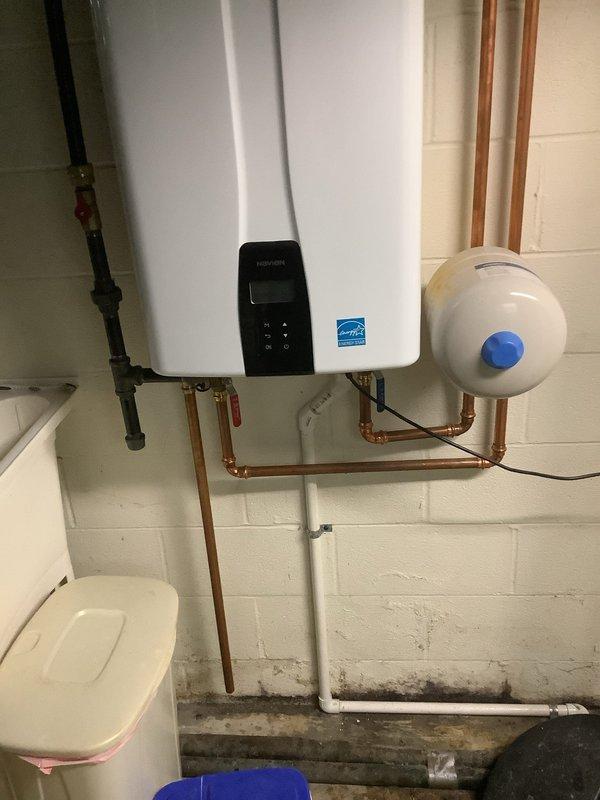 Performed scheduled maintenance flush on Navien tankless water heater unit located in basement utility area. Isolated unit from water supply, connected service hoses, and circulated descaling solution through heat exchanger to remove mineral buildup and calcium deposits. Flushed system thoroughly with clean water to clear all descaling agent residue. Inspected copper supply and return piping connections, expansion tank, and all associated valves for proper operation and signs of leakage. Verified unit operation upon completion, confirmed proper flow rates, and ensured digital control panel displayed normal operating parameters. System returned to service with optimal performance restored.