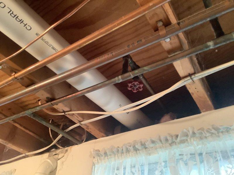 Conducted on-site evaluation of exterior hose bibb requiring replacement. Inspected existing copper water supply line configuration in basement ceiling area, including shutoff valve accessibility and pipe routing. Assessed structural conditions of exposed joists and plumbing infrastructure to determine optimal replacement approach. Documented existing installation with photographs showing copper supply piping, red-handled shutoff valve, mounting locations, and surrounding insulation placement. Provided complimentary estimate for complete outside spigot replacement including materials and labor.