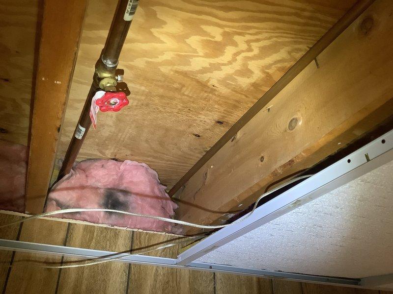 Conducted on-site evaluation of exterior hose bibb requiring replacement. Inspected existing copper water supply line configuration in basement ceiling area, including shutoff valve accessibility and pipe routing. Assessed structural conditions of exposed joists and plumbing infrastructure to determine optimal replacement approach. Documented existing installation with photographs showing copper supply piping, red-handled shutoff valve, mounting locations, and surrounding insulation placement. Provided complimentary estimate for complete outside spigot replacement including materials and labor.
