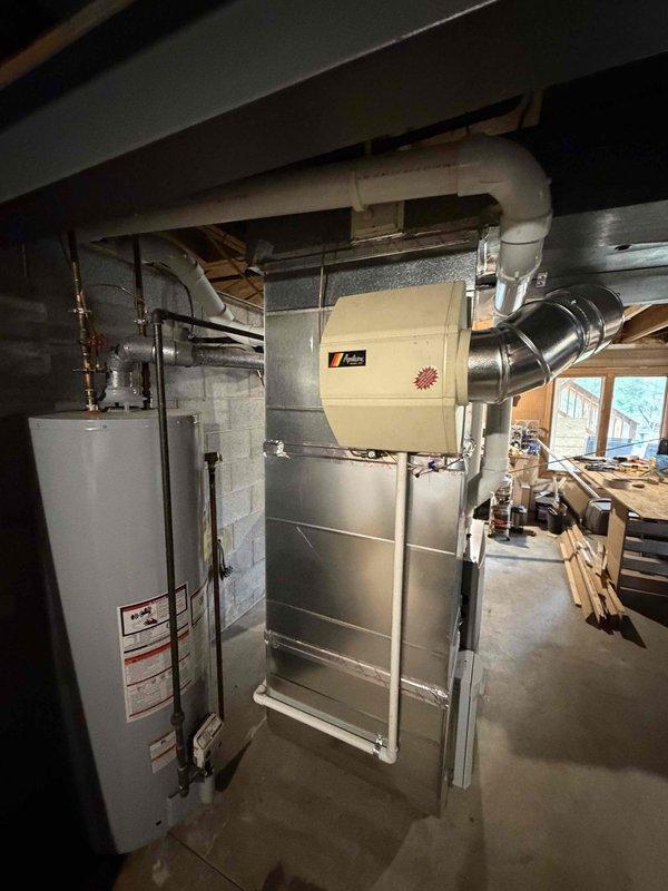 Completed installation of a 90% AFUE furnace in residential basement location. Installed new air handler unit with integrated humidifier system and connected white PVC venting for condensate drainage. Mounted carbon monoxide alarm in utility area per code requirements to ensure safe operation of new gas-fired equipment. All ductwork connections secured and system tested for proper operation.