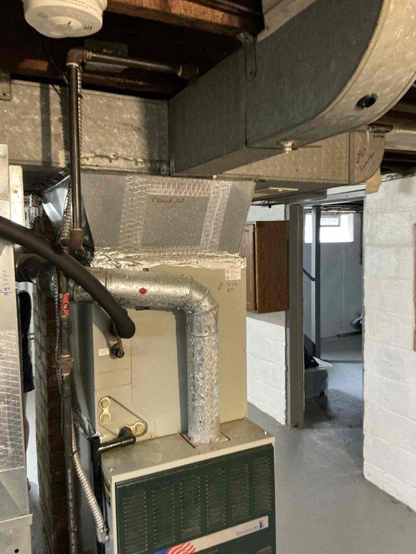 Completed comprehensive assessment for furnace replacement on 26-year-old heating system that had reached end of serviceable life. Evaluated existing HVAC equipment including outdoor condensing unit positioned on concrete pad with proper landscaping clearances and basement furnace installation with associated ductwork and plenum assembly. Documented current system configuration, gas line routing, and existing duct connections to prepare detailed replacement quote for new high-efficiency heating equipment.