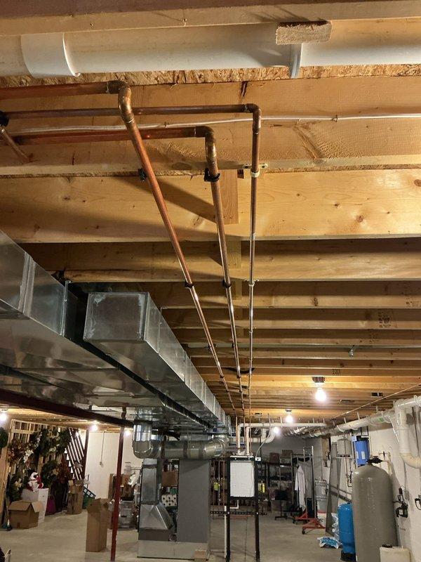 Responded to a service call for a tankless water heater requiring repair at a residential property. Upon arrival, performed diagnostic inspection of the Navien NPE-240A2 tankless unit installed in the basement mechanical room. Assessed the unit's operational status, inspected copper supply and return piping connections, verified proper venting configuration, and examined mounting and support systems. Documented existing conditions of the tankless water heater installation and surrounding mechanical systems for service records.