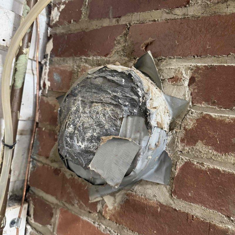 Responded to service call for furnace making abnormal noise during and after heating cycles. Upon inspection, discovered severely deteriorated dryer vent ductwork penetrating through exterior brick wall with extensive damage to metal housing and significant lint accumulation inside the vent system. The ductwork insulation showed heavy degradation with multiple tears and layers separated from original position. Documented conditions with photos showing compromised vent integrity, torn metal fragments, and buildup of debris that could potentially impact HVAC system operation and create safety concerns. Assessed whether issue was related to scheduled maintenance appointment to determine appropriate next steps for repair.