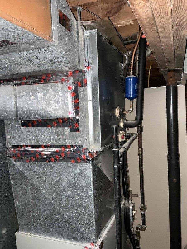 Conducted comprehensive evaluation of 30-year-old residential HVAC system including outdoor condensing unit and indoor air handler for replacement estimate. Assessed existing equipment condition, documented current installation configuration with exterior unit positioned on rubber pad with stone surround and glass block foundation windows, and inspected basement air handler with associated ductwork, copper refrigerant lines, and filter drier components to provide accurate replacement recommendations.