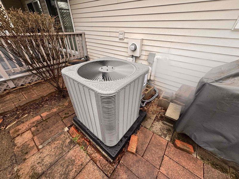 Completed installation of a 90% AFUE gas furnace with 5-ton air conditioning system and condensate pump at residential property. New outdoor condenser unit positioned on rubber isolation pad over existing paver patio adjacent to home's electrical service panel. Installed reversing valve solenoid assembly on air handler unit to enable proper refrigerant flow control. System tested and verified operational with all components functioning within manufacturer specifications.