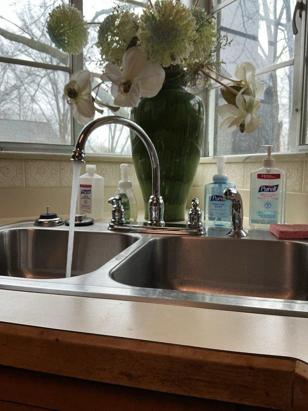Installed customer-supplied kitchen faucet fixture on double-basin stainless steel sink. Connected braided flexible supply lines to existing copper water supply pipes and verified proper water flow and drainage with no leaks detected upon completion.