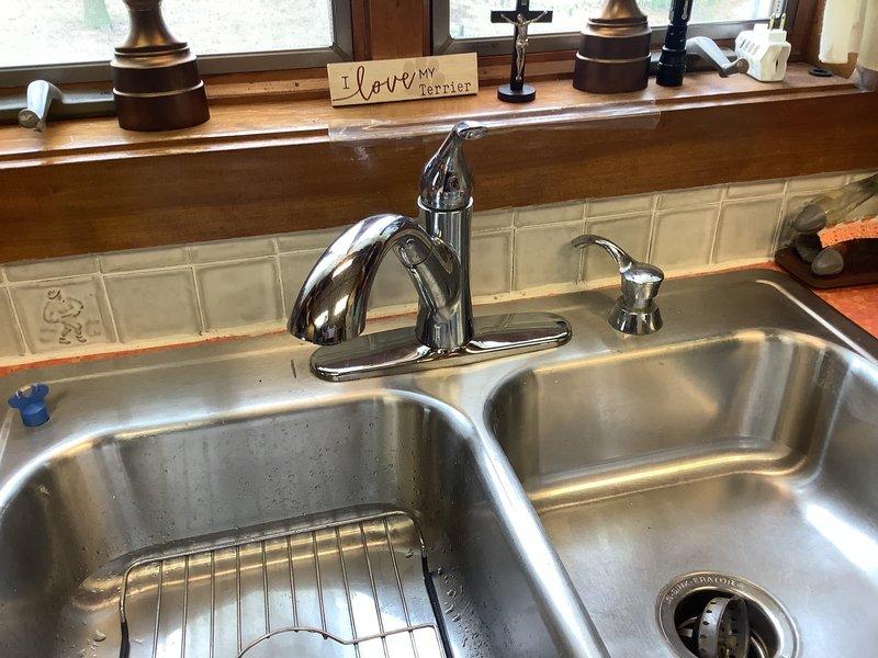 Responded to low water flow issue affecting both hot and cold water at kitchen faucet. Inspected chrome pull-down faucet at double-basin stainless steel sink and determined aerator was clogged with mineral deposits and debris. Removed and cleaned aerator, restoring full water pressure to both hot and cold lines.