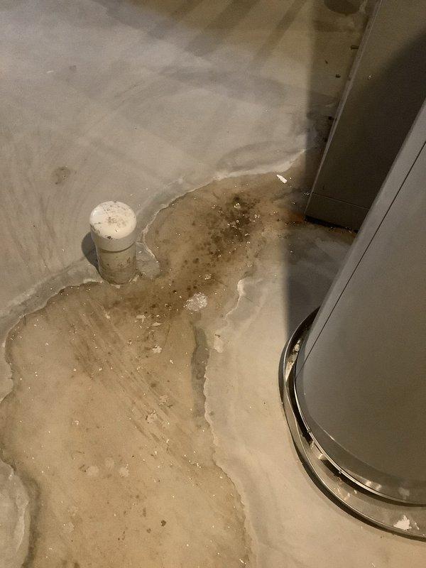 Responded to service call for central air conditioning unit experiencing water leakage during operation. Upon inspection, found significant water pooling on utility room floor surrounding equipment. Identified clogged condensate drain line as source of overflow, evidenced by accumulated debris and sediment visible within drain opening. Cleared blockage from condensate drain system, flushed line to restore proper drainage, and verified unit now discharging condensate appropriately without further leakage.