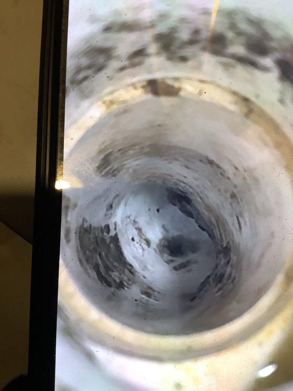 Responded to service call for central air conditioning unit experiencing water leakage during operation. Upon inspection, found significant water pooling on utility room floor surrounding equipment. Identified clogged condensate drain line as source of overflow, evidenced by accumulated debris and sediment visible within drain opening. Cleared blockage from condensate drain system, flushed line to restore proper drainage, and verified unit now discharging condensate appropriately without further leakage.
