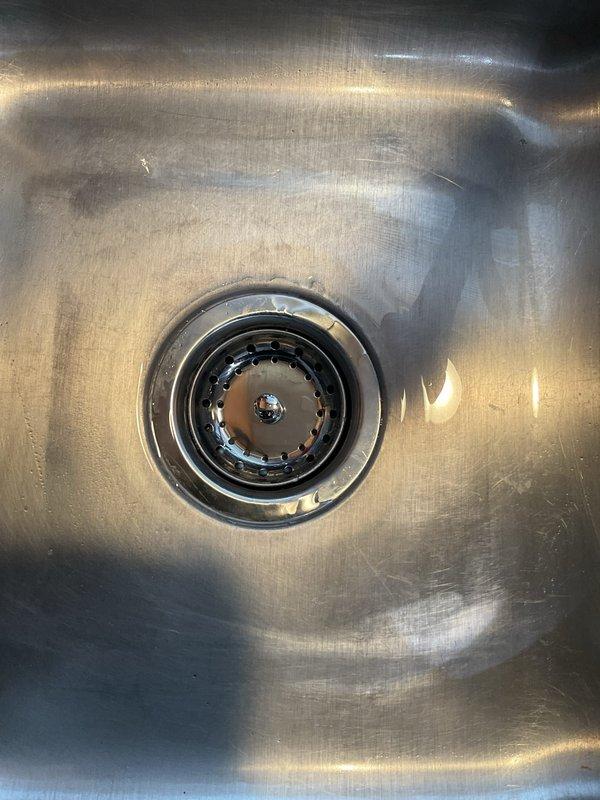Addressed multiple leaks and corroded piping under kitchen sink by replacing both basket strainers, removing deteriorated trap assembly and installing new trap with two-part tray waste configuration. Installed new wye branch tailpiece for dishwasher connection and performed drain line snaking to ensure proper flow and eliminate any blockages in the system.