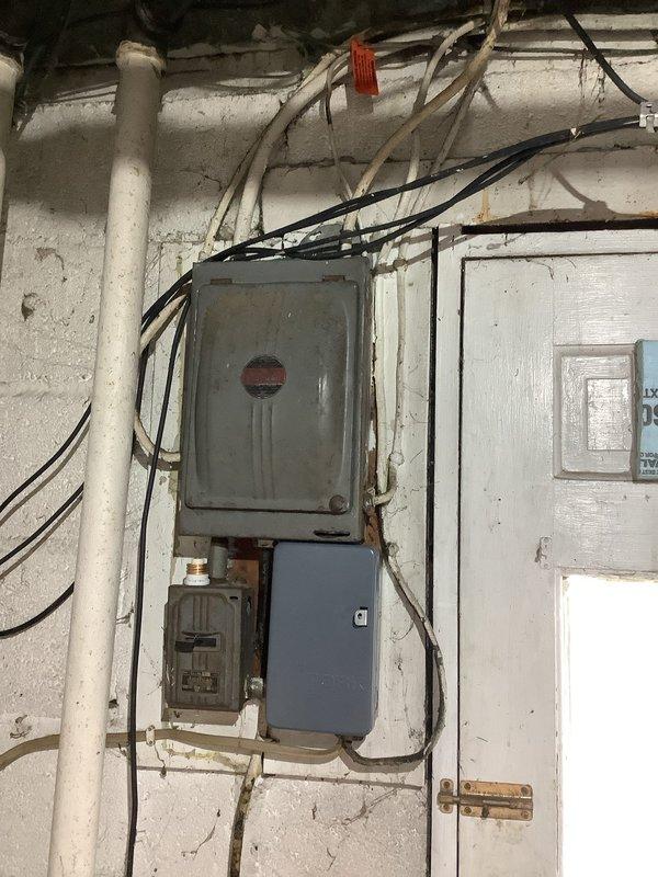 Conducted comprehensive electrical assessment of 6-unit apartment building to provide estimate for complete service upgrade. Evaluated existing service entrance, determined requirements for new drop band installation from street to main service entrance point, and assessed current meter socket configuration for replacement with new individual metering for each unit. Inspected aging electrical panels throughout building, noting deteriorated equipment with significant rust and wear requiring full replacement with new main panels for all six units and new sub-panels as needed. Examined existing conduit routing and wiring infrastructure in common areas, including detailed inspection of laundry room electrical systems to verify code compliance and safety conditions. Documented all findings with photographs of exterior service entrance area showing current meter locations and interior utility spaces displaying existing panel conditions and wiring configurations to support comprehensive proje