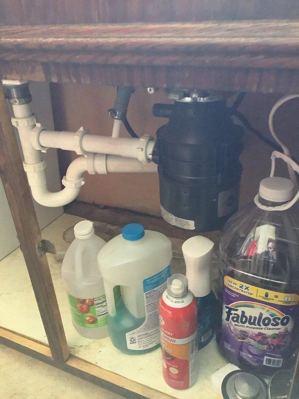 Responded to clogged kitchen sink in 1960s-era home. Upon arrival, found double-basin stainless steel sink with standing water in both basins—left basin contained relatively clear water while right basin had dark, murky water with visible sediment and debris accumulation. Inspected under-sink plumbing configuration which included white PVC P-trap assembly connected to garbage disposal unit. Cleared blockage from drain line, restored proper drainage to both basins, and verified garbage disposal operation. System tested and functioning normally upon completion.