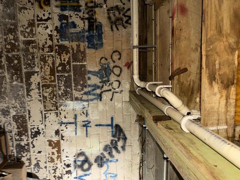 Met with inspector at 8am as scheduled to review plumbing installation in unfinished utility and attic spaces. Inspection covered white PVC drainage system with multiple branch configurations, T-joints, and elbows secured to wooden framing with gray plastic mounting brackets. Vertical and horizontal pipe runs were examined throughout both levels, including connections between tiled utility area and upper floor rough-in. All plumbing infrastructure was presented for code compliance verification and approval.