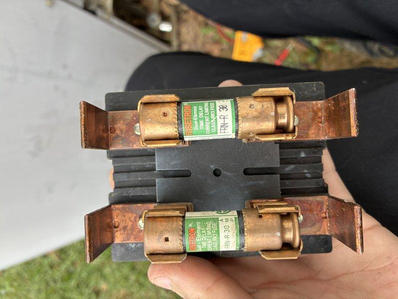 Completed routine MVP cooling maintenance visit on Carrier outdoor condensing unit. Inspected refrigerant lines, electrical disconnect, and overall system operation. Examined and documented electrical fuses showing signs of oxidation and wear on copper terminals and end caps, indicating extended service life and potential need for future replacement monitoring.