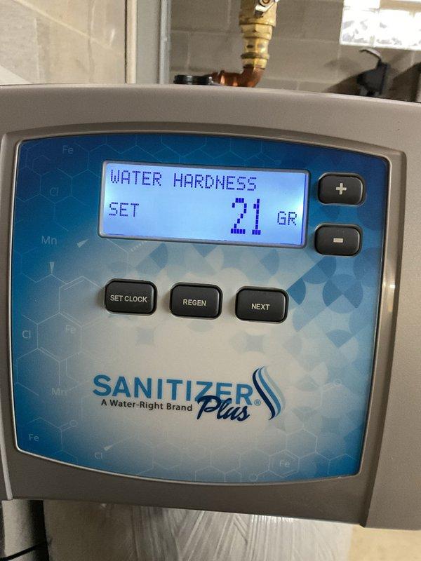 Completed salt delivery service for water softener system at residential property. Delivered three bags of water softener salt from warehouse inventory to basement utility area and placed them in front of existing Water-Right Sanitizer Plus dual-tank water treatment system. Verified system control panel displayed proper water hardness setting of 21 grains and confirmed adequate salt supply for continued operation of the softening equipment.