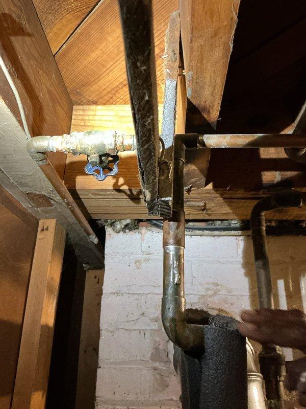 Responded to service call for leaking water heater in residential property over 40 years old. Upon inspection, confirmed active leak from existing water tank requiring immediate replacement. Assessed attic/crawl space installation location with existing plumbing infrastructure including copper water lines, shutoff valves, and venting system showing age-related corrosion and deterioration. Documented existing conditions including corroded vent piping with significant discoloration and greenish patina on metal components indicating extended moisture exposure. Provided estimate for new water heater installation, discussed available financing options and membership program benefits with customer. Established new service account per customer request and scheduled follow-up for installation.
