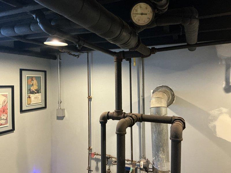 Conducted comprehensive boiler system evaluation and documented existing conditions for financing assistance application. Assessment revealed aging plumbing infrastructure with extensive corrosion on copper piping, deteriorated pipe fittings, and oxidized components throughout the heating system. Photographed overhead piping configuration, pressure gauges, shut-off valves, and basement mechanical systems to support loan application documentation for equipment replacement.