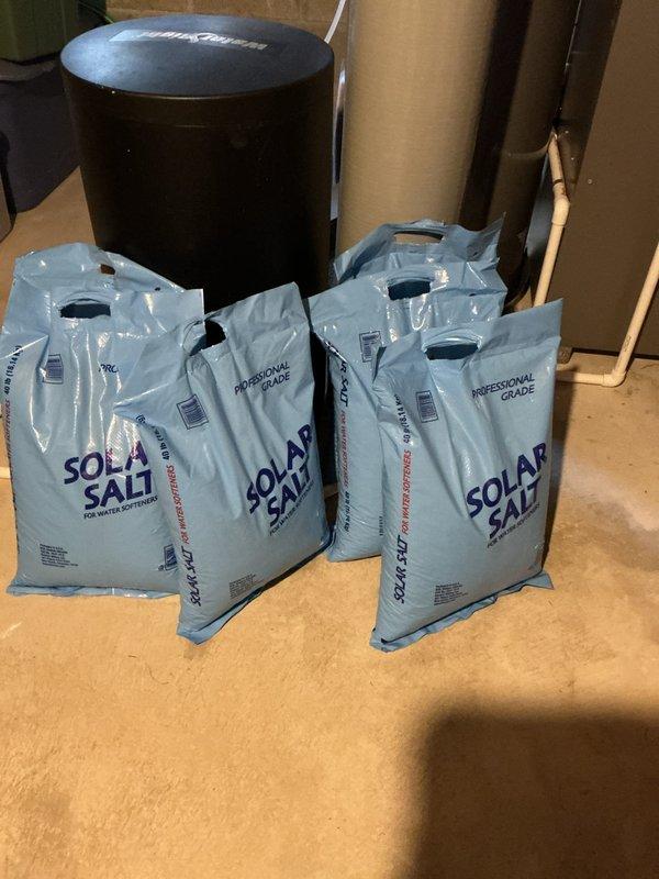Delivered four bags of professional-grade solar salt to the residence and assisted with loading the water softener system. Inspected the water softener tank and brine basin, noting normal sediment accumulation in the sump pit and proper standpipe positioning. Successfully replenished salt supply to ensure continued operation of the water treatment system.