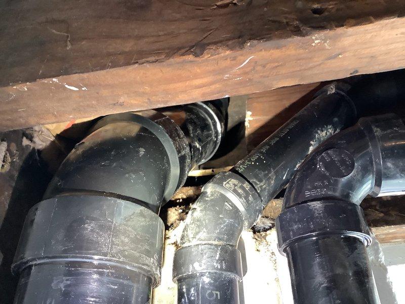 Replaced damaged ABS drainage piping in basement, including cutting and removing 3" pipe on first floor at cabinet location and 6" above the 4" upsize transition point in basement. Cut and replaced 1 1/2" kitchen drain line. Installed new ABS piping to repair cracked fitting and removed temporary tape from 45-degree elbow in basement. System was pressure tested upon completion to verify all leaks were eliminated and drainage system restored to proper function.