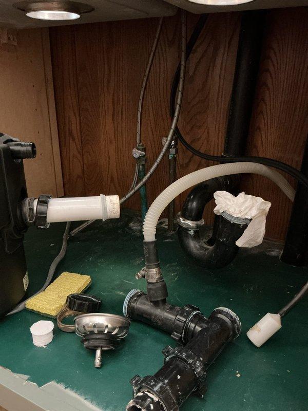 Re-plumbed kitchen sink following new countertop installation, including reinstallation of garbage disposal unit and all associated drain assemblies. Disassembled existing disposal and drain components, cleaned and inspected all fittings and connections, then reassembled the complete under-sink plumbing system with proper alignment to accommodate the new counter configuration.