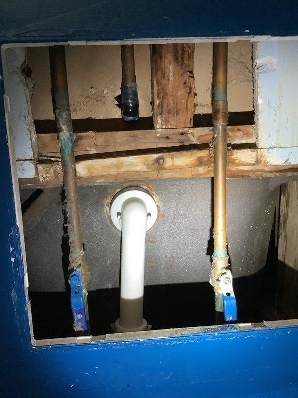 Responded to water leak emergency where shower faucet was allowing water to run down the back of the fixture into drop ceiling, causing water accumulation on basement floor below. Inspected plumbing access point beneath bathroom revealing mix of PVC and aged copper piping with visible corrosion, assessed bathtub fixtures showing mineral buildup and water spotting, and documented compromised seal at faucet mounting point requiring repair to prevent further water intrusion and structural damage.