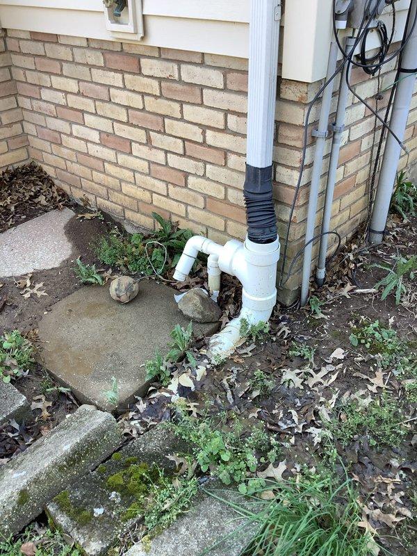 Responded to emergency service call for sump pump system causing water flooding in yard and adjacent property. Inspected basement sump pump installation and identified discharge system failure allowing water to overflow. Assessed exterior drainage configuration including downspout connections and PVC discharge piping extending from foundation. Documented existing conditions showing weathered concrete floor with mineral deposits and moisture staining around sump pit, standing water in basin, and compromised discharge line routing. Evaluated exterior discharge terminus where flexible ribbed piping connected to PVC elbow assembly was directing water improperly, contributing to yard flooding. Provided estimates for kitchen and bathroom faucet replacements as requested. Assessed dehumidifier unit for operational issues per homeowner request.