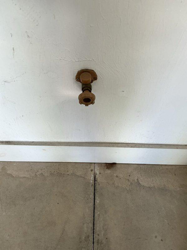 Responded to plumbing service call for multiple outdoor spigot issues. Addressed malfunctioning garage spigot that would not shut off properly, requiring valve inspection and repair. Evaluated capped-off spigot located behind the condo unit that was non-operational. Assessed two additional outside spigots for proper function. Documented conditions of all fixtures with photographs showing brass valve components, mounting locations on exterior siding, and surrounding areas including foundation landscaping.