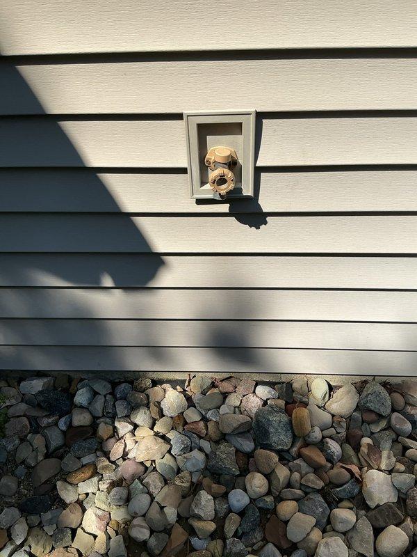 Responded to plumbing service call for multiple outdoor spigot issues. Addressed malfunctioning garage spigot that would not shut off properly, requiring valve inspection and repair. Evaluated capped-off spigot located behind the condo unit that was non-operational. Assessed two additional outside spigots for proper function. Documented conditions of all fixtures with photographs showing brass valve components, mounting locations on exterior siding, and surrounding areas including foundation landscaping.