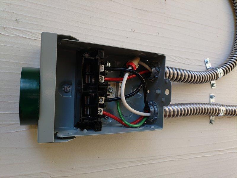 Installed a customer-provided ChargePoint Level 2 EV charger in the garage with load management solution to avoid panel upgrade to 200 amps. Due to existing panel capacity constraints per load calculations, integrated a SimpleSwitch load sharing device between the electric range circuit and new EV charger circuit to prioritize power distribution. Ran new EV charging circuit from panel to right side, terminating in right corner of garage near existing stack pipe using 4-11/16" junction box with THHN conductors in conduit. Installed code-required disconnect switch for hardwired charger connection. Modified existing range circuit by junctioning and relocating to accommodate SimpleSwitch installation, ensuring proper load management between appliances.