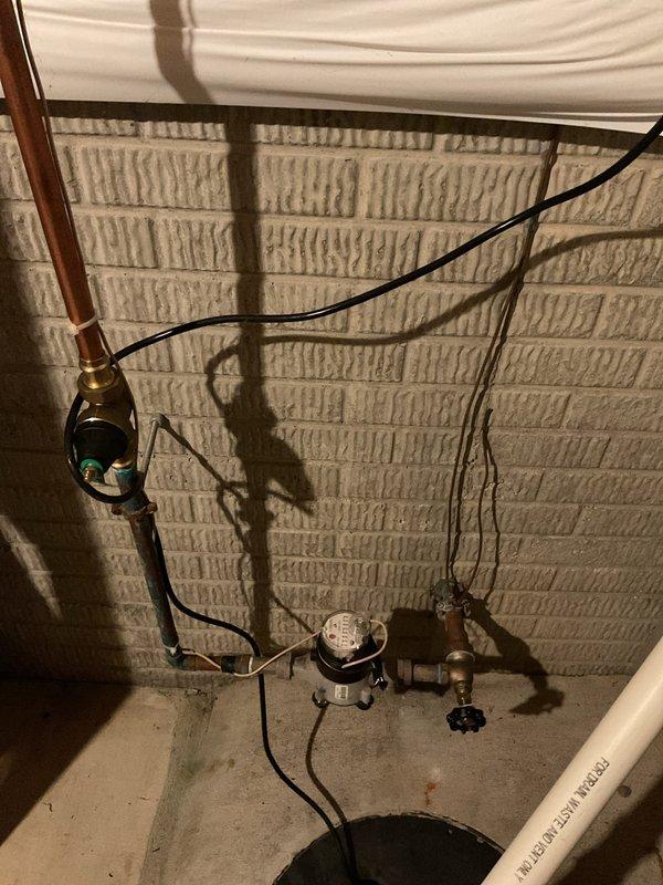 Responded to service call for sump pump backup issues. Upon inspection, found sump pump experiencing recurring drainage problems despite previous flushing attempts. Evaluated sump pump assembly, discharge piping, and check valve system for blockages or mechanical failure. Assessed condition of existing pump motor and float switch operation. Photographed installation showing sump basin, electrical connections, copper and PVC discharge lines, and associated plumbing infrastructure in basement utility area. Discussed diagnostic findings with customer and provided recommendations for either snaking the discharge line to clear potential obstruction or replacing the sump pump unit depending on severity of blockage and pump condition.