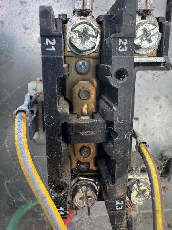 Completed preventative maintenance tune-up on 15-year-old air conditioning system. Inspected contactor assembly showing moderate wear with tarnishing on brass terminals and contact points, confirmed proper electrical connections on numbered terminals 21 and 23, and verified all wiring integrity. Unit operating within normal parameters following standard maintenance protocol.