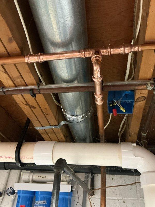 Responded to a water leak at the main supply line feeding the hot water tank in a home originally constructed in 1963. Upon inspection, identified a severely corroded and actively leaking elbow joint on the galvanized piping upstream of the water heater. The corrosion had compromised the fitting integrity, resulting in water seepage that had caused visible damage to the surrounding wall and concrete floor surfaces.

Shut off the main water supply at the meter to isolate the system. Removed the failed elbow joint and surrounding corroded section of galvanized pipe. Replaced the deteriorated components with new copper piping and fittings, utilizing proper soldering techniques to ensure watertight connections. Installed appropriate transition fittings to integrate the new copper section with the existing galvanized main line and downstream plumbing infrastructure.

Restored water supply and pressure-tested all new connections to verify leak-free operation. Confirmed proper water flow to t