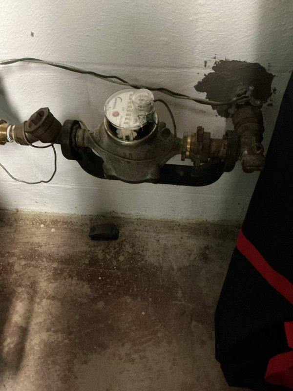 Responded to a water leak at the main supply line feeding the hot water tank in a home originally constructed in 1963. Upon inspection, identified a severely corroded and actively leaking elbow joint on the galvanized piping upstream of the water heater. The corrosion had compromised the fitting integrity, resulting in water seepage that had caused visible damage to the surrounding wall and concrete floor surfaces.

Shut off the main water supply at the meter to isolate the system. Removed the failed elbow joint and surrounding corroded section of galvanized pipe. Replaced the deteriorated components with new copper piping and fittings, utilizing proper soldering techniques to ensure watertight connections. Installed appropriate transition fittings to integrate the new copper section with the existing galvanized main line and downstream plumbing infrastructure.

Restored water supply and pressure-tested all new connections to verify leak-free operation. Confirmed proper water flow to t
