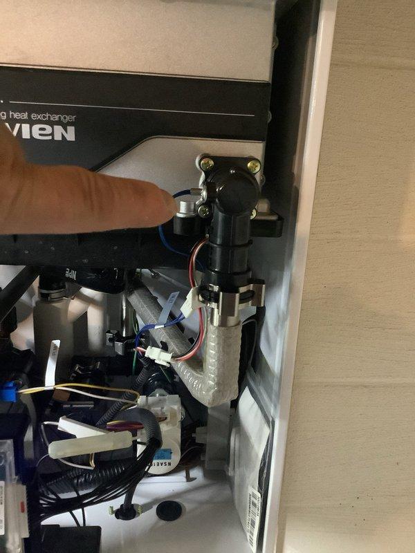 Responded to service call for Navien tankless water heater experiencing intermittent temperature fluctuations and unusual noise during operation. Upon inspection, opened access panel and examined internal components including heat exchanger, blower assembly, and control board. Identified potential issue with flow sensor or gas valve solenoid causing system to cycle improperly. Inspected all wiring connections, gas line connections with flexible connector and shut-off valve, and copper water supply lines with brass fittings. Verified digital control panel displaying 120°F setpoint. Documented internal component condition with photos for reference. Unit mounted in basement utility area with adequate ventilation and proper venting configuration.