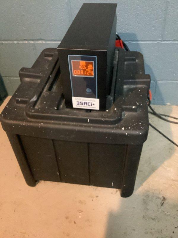 Responded to service call for non-operational sump pump system and failed battery backup unit in 50-year-old residence. Upon inspection, found existing battery backup UPS system positioned on sump basin with degraded performance and battery failure. Assessed sump pump operation within basin, noting proper water level management and functional discharge piping. Tested and diagnosed battery backup system failure, identifying need for replacement or repair of UPS unit to restore emergency pumping capability during power outages. Documented current system configuration including pump positioning, discharge line routing, and backup power connection for future service reference.