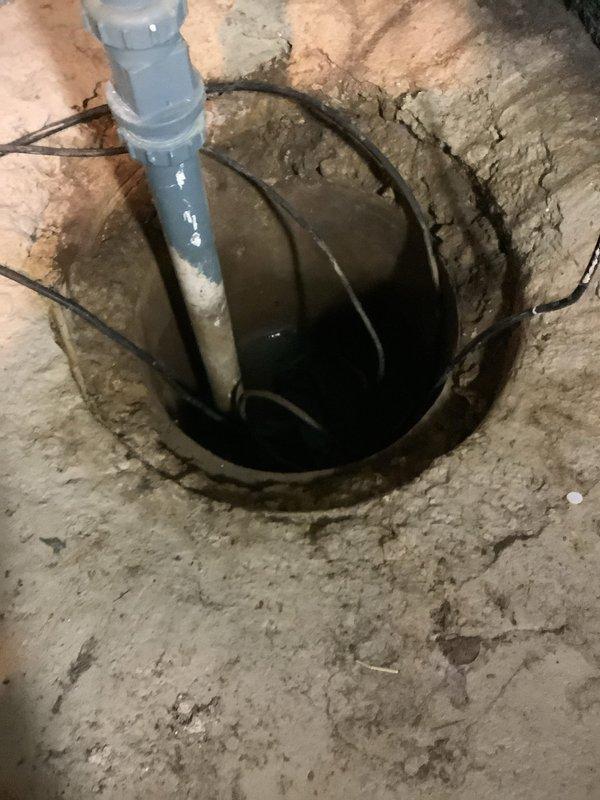 Responded to service call for non-operational sump pump system and failed battery backup unit in 50-year-old residence. Upon inspection, found existing battery backup UPS system positioned on sump basin with degraded performance and battery failure. Assessed sump pump operation within basin, noting proper water level management and functional discharge piping. Tested and diagnosed battery backup system failure, identifying need for replacement or repair of UPS unit to restore emergency pumping capability during power outages. Documented current system configuration including pump positioning, discharge line routing, and backup power connection for future service reference.
