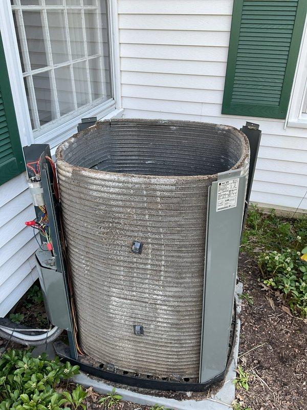 Completed MVP cooling maintenance visit on cylindrical condenser unit with ribbed aluminum coil design. Performed standard preventive maintenance inspection of outdoor unit positioned on concrete pad against house exterior. Documented equipment condition showing normal weathering and minor dirt accumulation on coil fins consistent with outdoor exposure. Unit operational with all components functioning within normal parameters. Access panels and electrical connections inspected and found secure. Photographed equipment for service records.