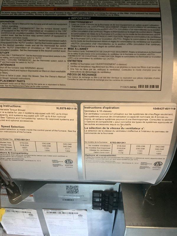 Conducted comprehensive evaluation of existing HVAC system for replacement estimate. Documented current equipment configuration including furnace interior components with model XL0376-601119 operating instructions and speed selection specifications. Assessed outdoor condensing unit condition, noting weathered cylindrical unit with vertical louvered panels positioned on concrete pad against exterior wall. Photographed refrigerant line routing from condensing unit through white protective conduit mounted to vinyl siding. Evaluated overall system age, condition, and replacement requirements to provide accurate equipment sizing and installation scope recommendations.