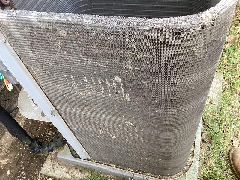 Responded to service call for furnace making loud noise following recent maintenance. Upon inspection, identified blower assembly as source of noise concern. Examined outdoor HVAC unit and found condenser coil heavily clogged with dirt, dust, and debris accumulation, significantly restricting airflow. Documented equipment condition showing substantial buildup on heat exchanger fins and weathered exterior components requiring attention.