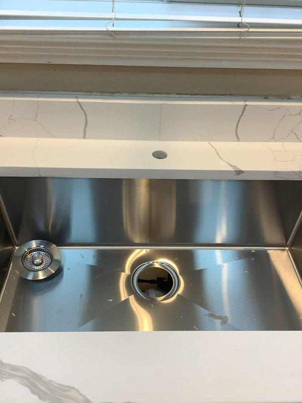 Completed kitchen sink conversion from double-basin to single-basin configuration with new undermount stainless steel sink installation. Installed garbage disposal unit and reconfigured drain plumbing with PVC P-trap assembly to accommodate new sink layout. Provided quote for whole house water filtration system as requested.