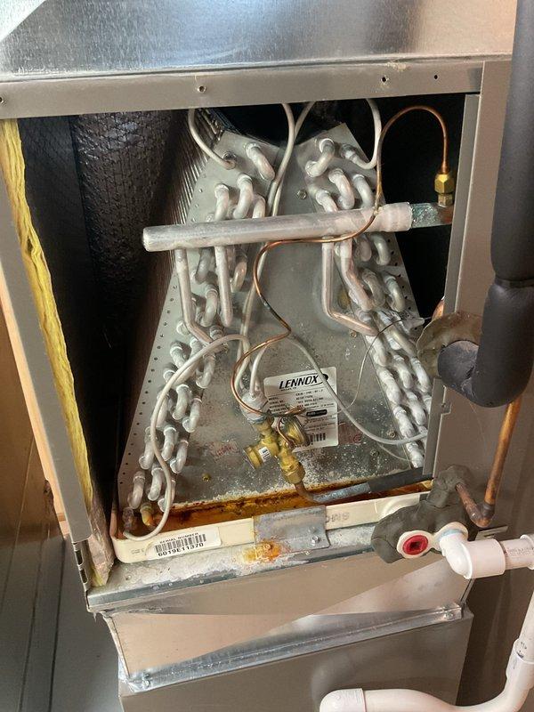 Completed comprehensive AC tune-up and maintenance on 5-year-old Lennox cooling system. Performed inspection of evaporator coil assembly, verified refrigerant lines and connections, checked condensate drain system with PVC drain line, and noted minor rust staining in drain pan area that requires monitoring. Inspected and documented pleated air filter condition in return air housing, confirmed all system components operational, and system performing within normal parameters for continued seasonal use.