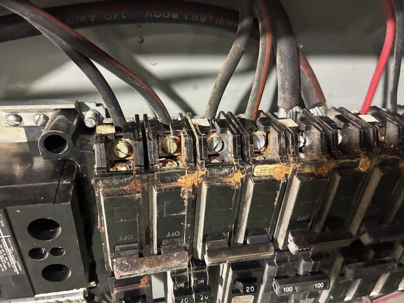 Responded to no-heat call on one-year-old heat pump with tripped circuit breaker. Upon inspection, discovered extensive rust and corrosion throughout the electrical panel affecting breaker terminals, bus bars, and mounting hardware, indicating significant moisture intrusion. Documented hazardous electrical conditions with corrosion present on terminal connections and recommended immediate panel replacement by licensed electrician before heat pump system could be safely restored to operation.