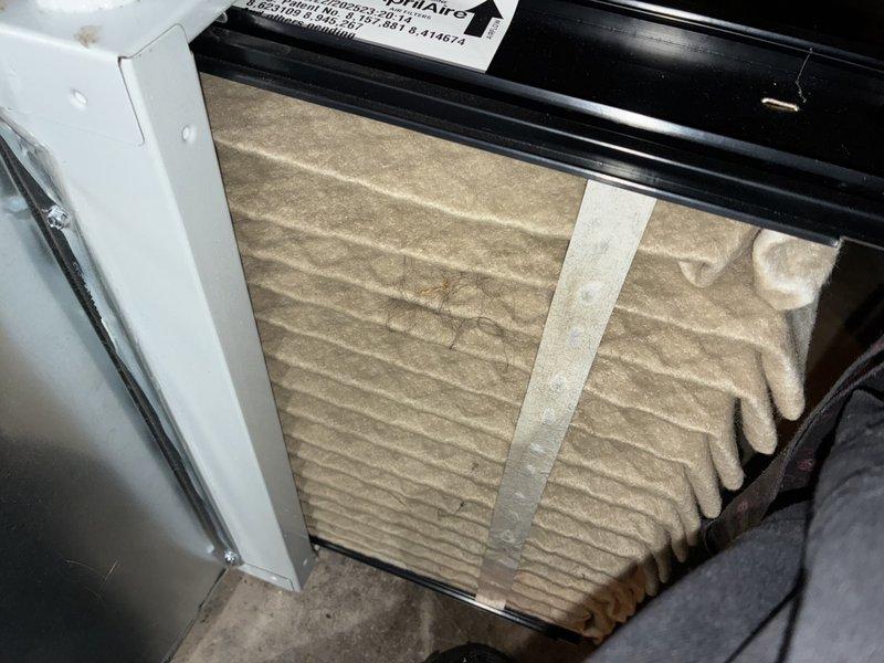 Performed routine HVAC maintenance on cooling system located in backyard. Inspected and evaluated air filter condition, noting dust accumulation and discoloration on pleated media. Examined condenser coil fins, observing minor debris accumulation and typical operational wear on aluminum fin surfaces. System components assessed and documented through photographic records for maintenance history.