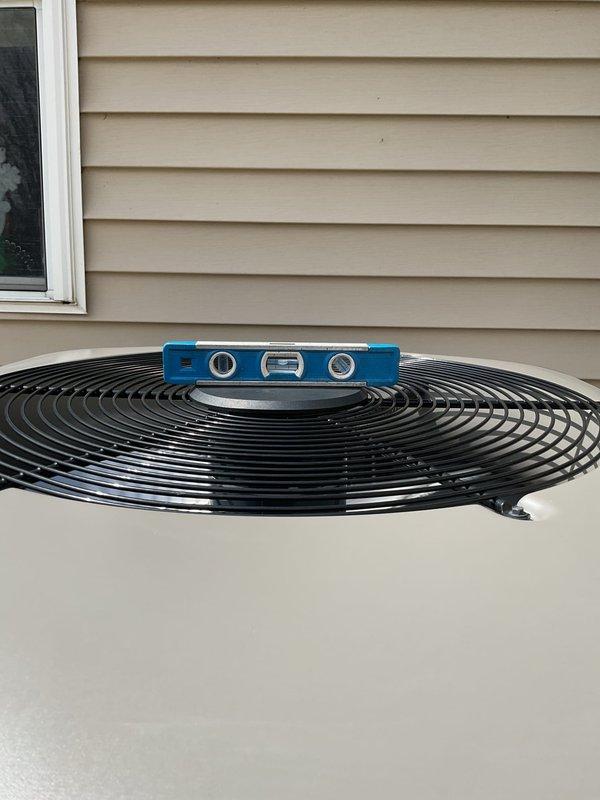 Completed routine maintenance inspection on 4-year-old air conditioning system for customer reporting slight operational noise. Performed visual assessment of outdoor condensing unit, verified proper installation on concrete pad with appropriate elevation and clearances, and confirmed unit levelness using precision measuring tools. All components appeared in good working condition with no immediate concerns identified.