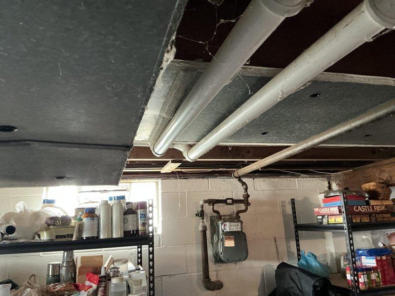 Conducted on-site evaluation for furnace replacement estimate in residential basement utility area. Documented existing HVAC infrastructure, plumbing connections, and spatial constraints including exposed ceiling joists, PVC drainage lines, and utility meter locations. Assessed clearance requirements and access pathways for equipment removal and installation, noting storage shelving and aged plumbing manifold assembly with corroded fittings in work vicinity. Provided comprehensive replacement recommendations and scheduling coordination per customer availability.